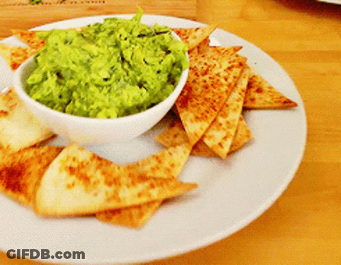 A Bowl Of Guacamole Sits On A Plate With Tortilla Chips GIF