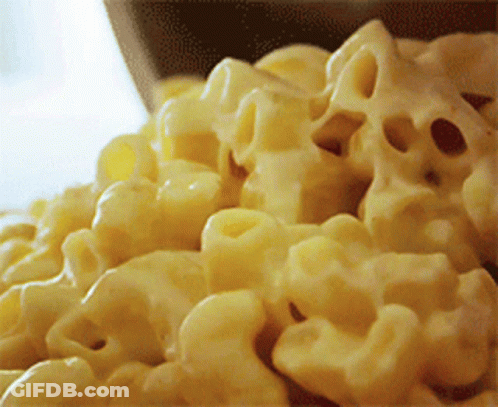 A Bowl Of Macaroni And Cheese Is Being Poured Into A Bowl GIF