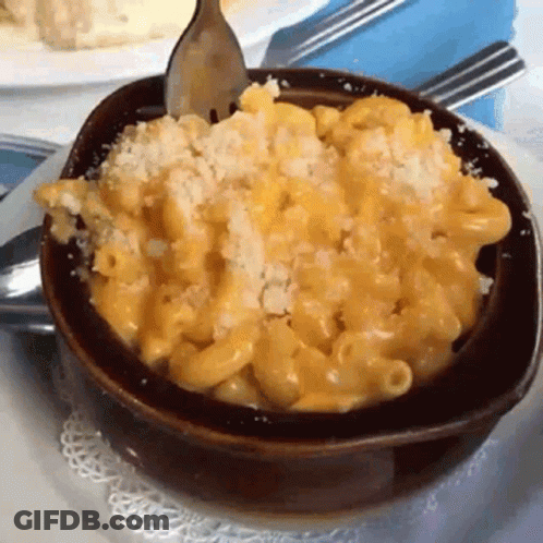 A Bowl Of Macaroni And Cheese On A Plate With A Fork GIF