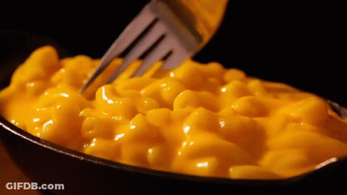 A Bowl Of Macaroni And Cheese With A Fork Sticking Into It GIF
