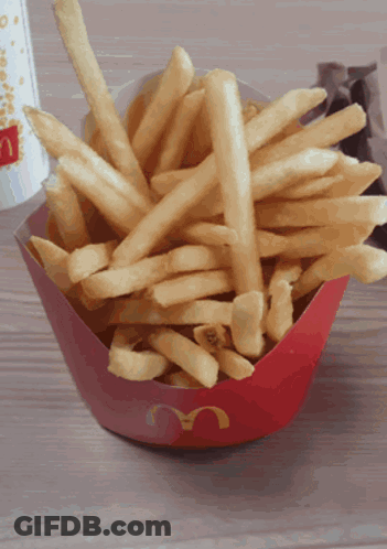 A Bowl Of Mcdonald 'S French Fries Sits On A Wooden Table GIF