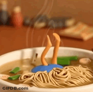 A Bowl Of Noodles With A Person 'S Legs Sticking Out Of It On A Table . GIF