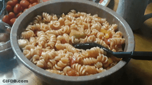 A Bowl Of Pasta With Tomatoes And A Spoon In It GIF