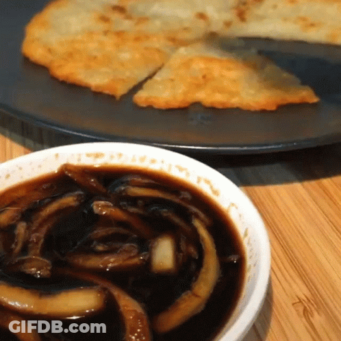 A Bowl Of Sauce Next To A Plate Of Food On A Table GIF