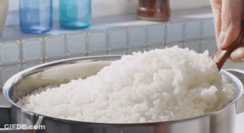 A Bowl Of White Rice Is Being Stirred With A Wooden Spoon GIF
