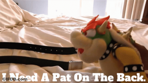 A Bowser Stuffed Animal Is Laying On A Bed With The Words " I Need A Pat On The Back " Above Him GIF