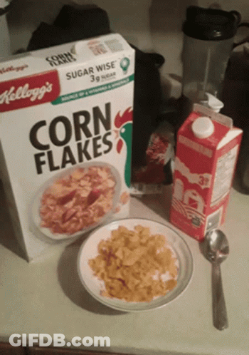 A Box Of Kellogg 'S Corn Flakes Next To A Plate Of Corn Flakes GIF