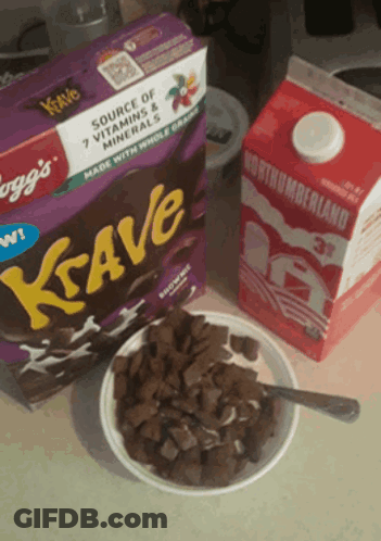 A Box Of Krave Cereal Sits Next To A Bowl Of Cereal And A Carton Of Milk GIF