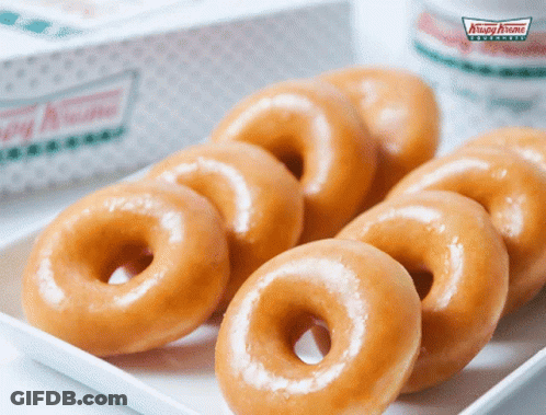 A Box Of Krispy Kreme Donuts Sits Next To A White Plate Of Donuts GIF