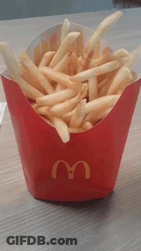 A Box Of Mcdonald 'S French Fries Sits On A Wooden Table GIF