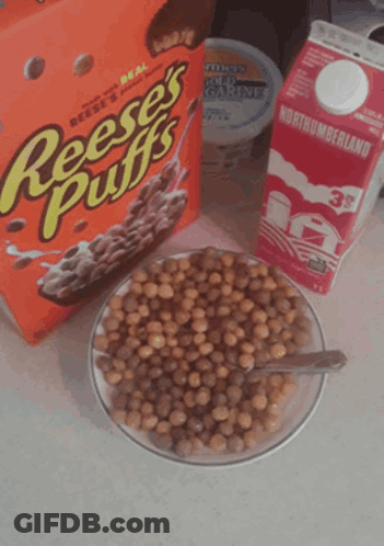 A Box Of Reese 'S Puffs Cereal Next To A Bowl Of Cereal And A Carton Of Milk GIF