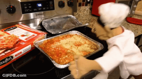 A Box Of Spaghettios Sits On A Stove Next To A Tray Of Lasagna GIF