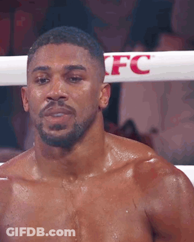 A Boxer Without A Shirt Is Standing In A Boxing Ring . GIF