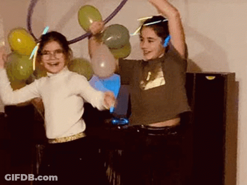 A Boy And A Girl Are Dancing In A Dark Room With Balloons And Glow In The Dark Headphones . GIF