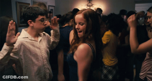 A Boy And A Girl Are Dancing In A Room Full Of People GIF