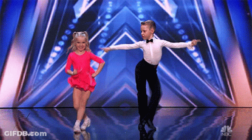 A Boy And A Girl Are Dancing On A Stage With A Nbc Logo In The Background . GIF