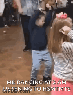 A Boy And A Girl Are Dancing Together In A Room . GIF