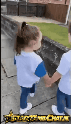 A Boy And A Girl Are Holding Hands On A Sidewalk With A Star Tamichat.in Logo Behind Them GIF