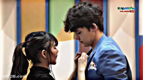 A Boy And A Girl Are Kissing In Front Of A Sign That Says Kapaliya GIF