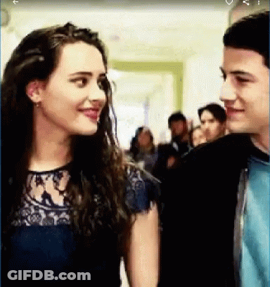A Boy And A Girl Are Looking At Each Other In A Hallway . GIF