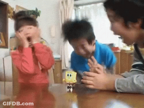 A Boy And A Girl Are Playing With A Spongebob Toy On A Table . GIF