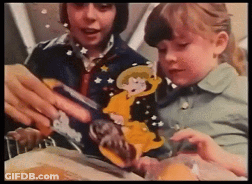 A Boy And A Girl Are Sitting At A Table Playing With A Cartoon Character . GIF