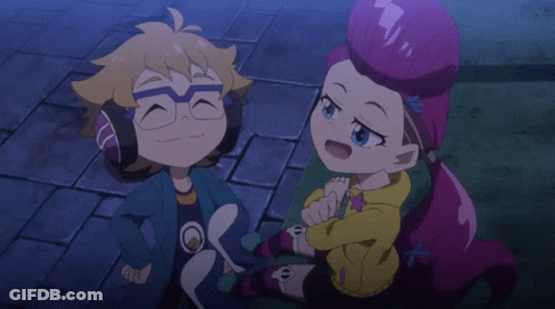 A Boy And A Girl Are Sitting Next To Each Other On A Brick Sidewalk GIF