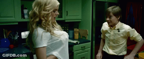 A Boy And A Girl Are Standing In A Kitchen With Green Cabinets GIF
