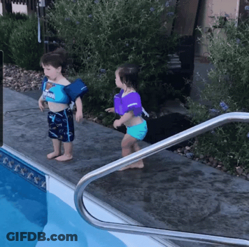 A Boy And A Girl Are Standing Next To A Pool Wearing Life Jackets GIF