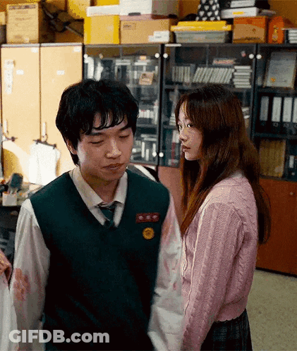 A Boy And A Girl Are Standing Next To Each Other In A Room Holding Hands . GIF