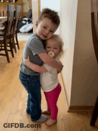 A Boy And A Girl Hugging Each Other In A Room GIF
