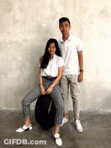 A Boy And A Girl Posing For A Picture With A Tire In The Background GIF