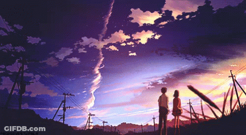 A Boy And A Girl Standing In Front Of A Sunset GIF