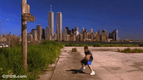 A Boy Dribbles A Basketball In Front Of A City Skyline GIF