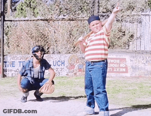 A Boy Holding A Bat Stands In Front Of A Sign That Says Next GIF