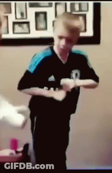 A Boy In A Black And Blue Adidas Shirt Is Holding A Wii Controller GIF