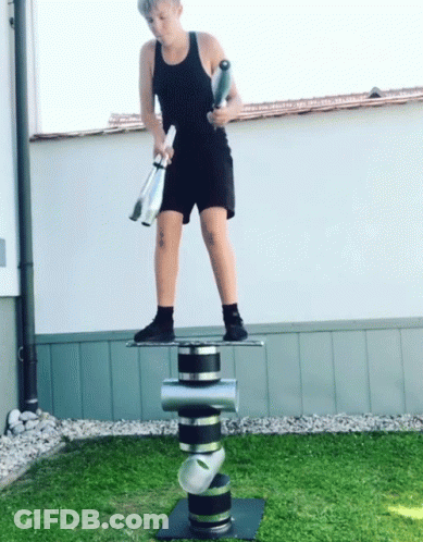 A Boy In A Black Tank Top And Shorts Is Juggling Clubs GIF