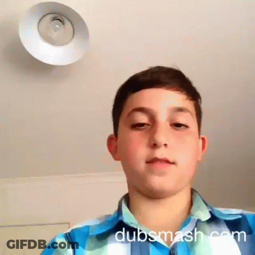 A Boy In A Blue And White Plaid Shirt Looks At The Camera With Dubsmash.com Written On The Bottom Right GIF