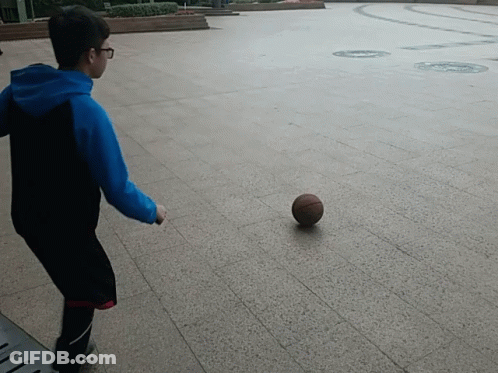 A Boy In A Blue Hoodie Is Kicking A Basketball On The Ground GIF