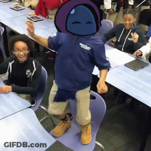 A Boy In A Blue Hoodie Is Standing On A Chair In Front Of A Group Of Children In A Classroom . GIF
