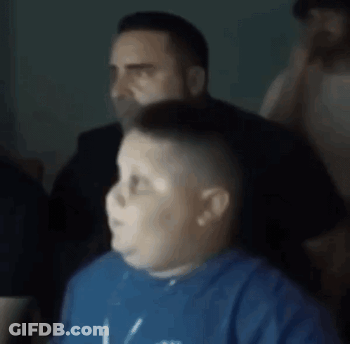 A Boy In A Blue Shirt Is Getting His Hair Cut By A Man In A Black Shirt . GIF