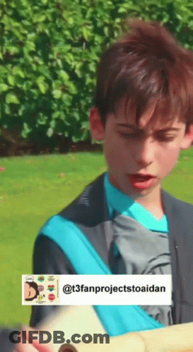 A Boy In A Blue Shirt Is Holding A Piece Of Paper In His Hand . GIF