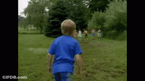 A Boy In A Blue Shirt Is Running In A Grassy Field GIF