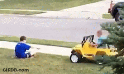 A Boy In A Blue Shirt Is Sitting On The Grass Next To A Yellow Toy Car . GIF