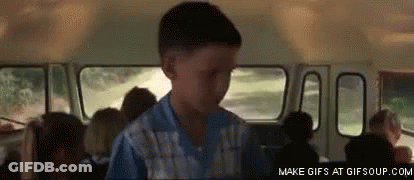 A Boy In A Blue Shirt Is Standing In A School Bus With Other Children . GIF