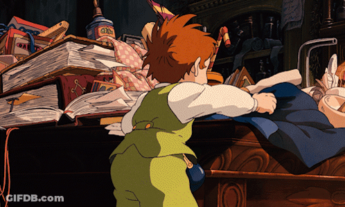 A Boy In A Green Vest Is Standing In Front Of A Pile Of Books And A Box That Says ' Gin ' On It GIF