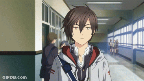 A Boy In A Hoodie Stands In A Hallway Looking At The Camera GIF