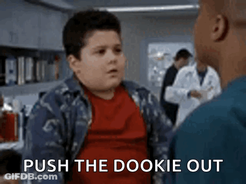 A Boy In A Red Shirt Is Talking To A Man In A Lab And The Words Push The Dookie Out Are Visible . GIF