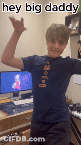 A Boy In A Relay Jeans Shirt Is Standing In Front Of A Computer Monitor GIF