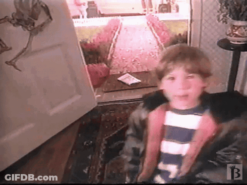 A Boy In A Striped Shirt Is Standing In Front Of An Open Door With The Letter B On The Bottom Right GIF
